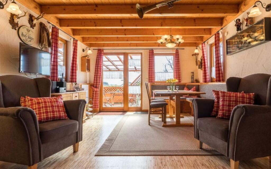 Themenbild von einer rustikal eingerichteten Ferienwohnung mit Hirschgeweihen an der Wand, rot weiß karierten Vorhängen und Sofakissen