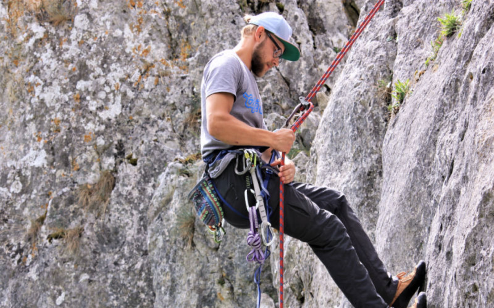 Themenbild eines Kletterers, der sich an einem Felsen abseilt.