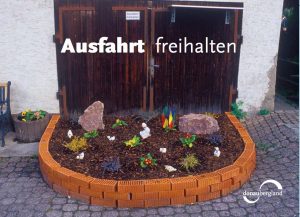 Donaubergland Postkartenmotiv mit angelegtem Blumenbeet direkt vor einer Ausfahrt.