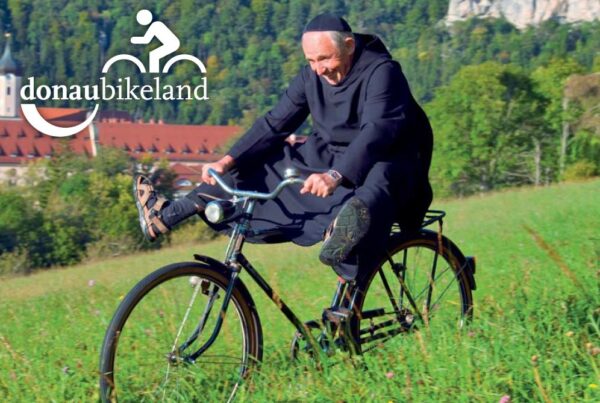 Bild von Mönch auf, der auf einer Wiese Fahrrad fährt und die Beine von sich streckt