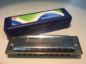 Bild einer Donauwellen Mundharmonika von Hohner mit blauem Etui mit dem Donauwellenlogo beklebt