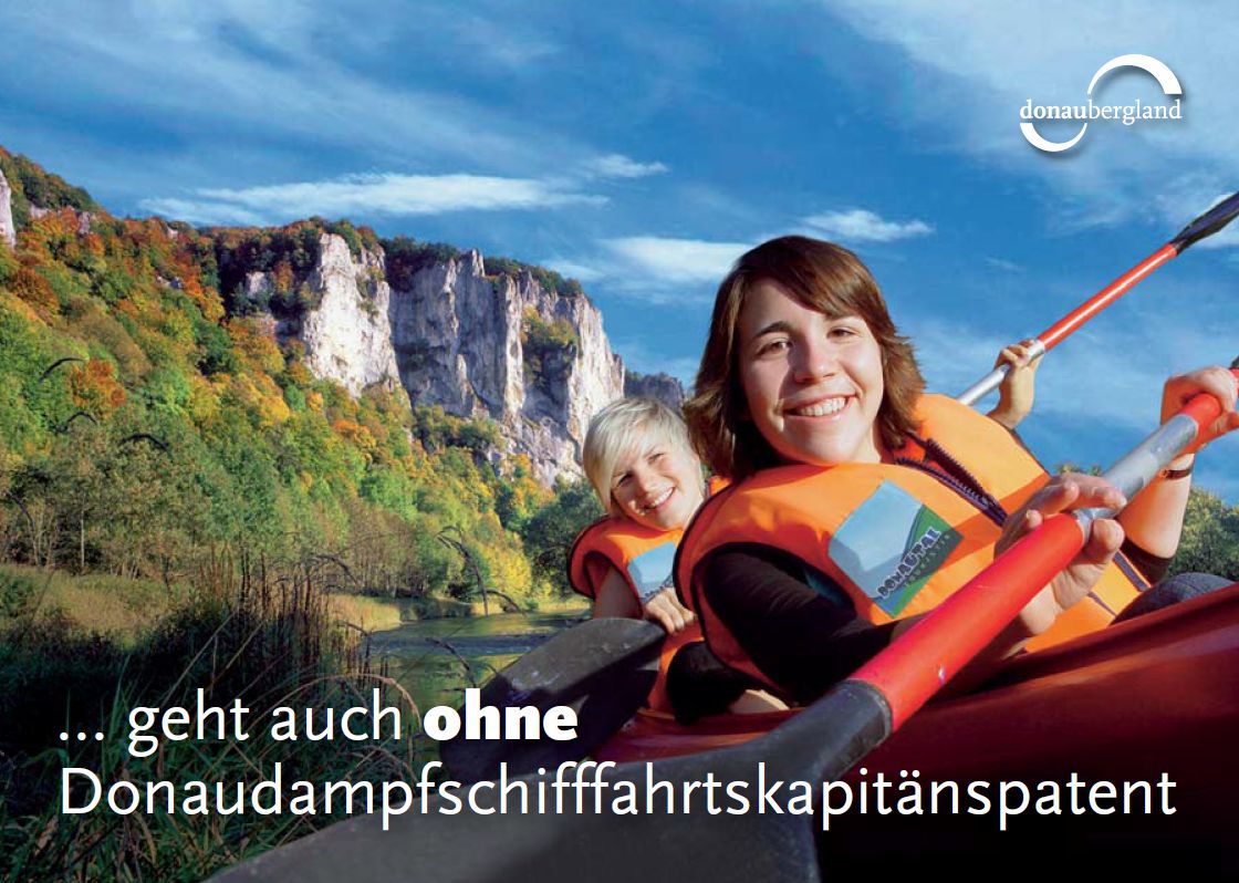 Donaubergland Postkartenmotiv mit zwei Frauen, die auf einem Gewässer vor Felsen paddeln.