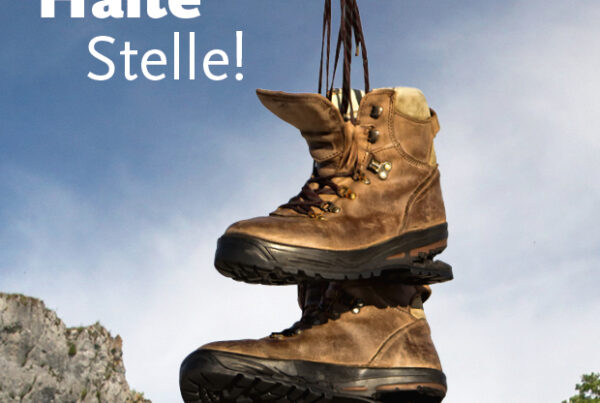 Donaubergland Postkartenmotiv mit hängenden Wanderschuhen an einem Haltestellenschild.