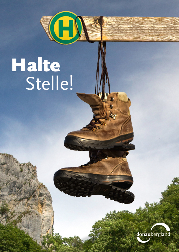 Donaubergland Postkartenmotiv mit hängenden Wanderschuhen an einem Haltestellenschild.