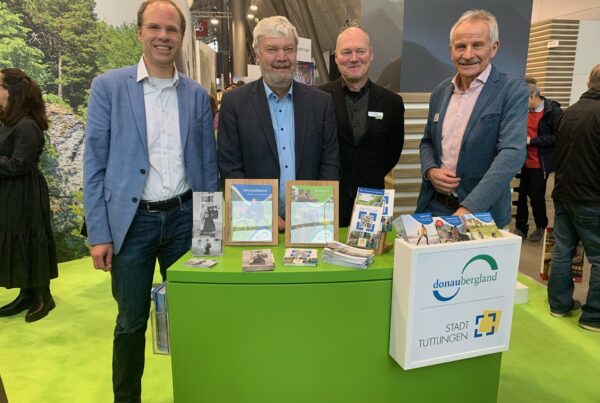 Foto von vier Personen hinter Messestand mit Besuch aus Denkingen