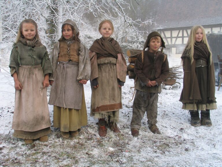 Bild von fünf Kindern im Winter vor Fachwerkgebäude und schneebedecktem Baum, die passend zu den Dreharbeiten zum Märchenfilm Sterntaler gekleidet sind. Sie sind alle dreckig und auf alt getrimmt gekleidet.