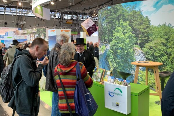 Foto vom Stand auf der CMT 2023, Donaubergland, mit Mann in Frack und Zylinder und weiteren Personen vor dem Stand.