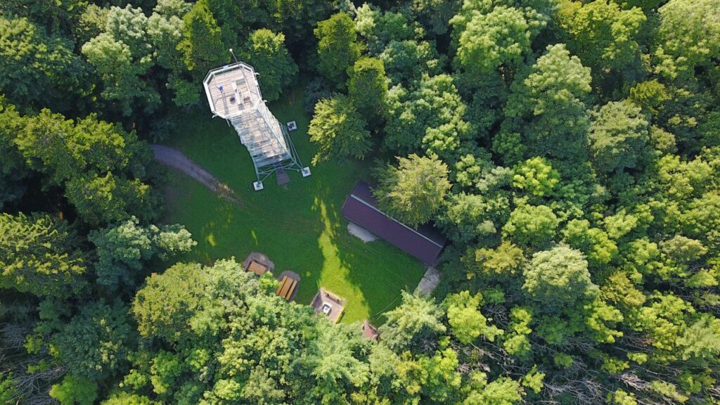 Luftaufnahme des Lembergturms umgeben von grünen Bäumen mit Sicht auf den Rastplatz und die Schutzhütte