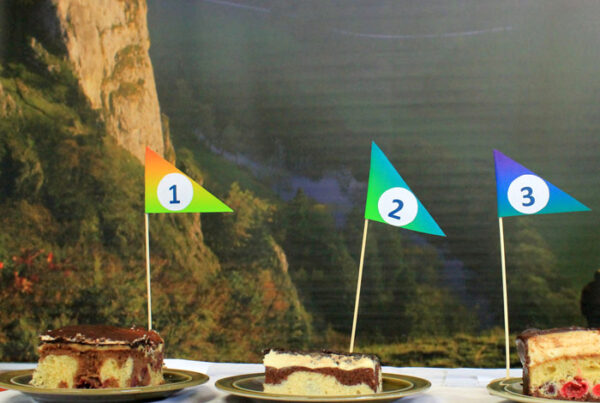 Bild von drei Stück Donauwelle mit Fähnchen mit den Zahlen eins bis drei. Im Hintergrund ist ein Landschaftsbild des Donautals zu erkennen.