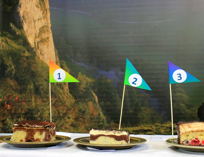 Bild von drei Stück Donauwelle mit Fähnchen mit den Zahlen eins bis drei. Im Hintergrund ist ein Landschaftsbild des Donautals zu erkennen.