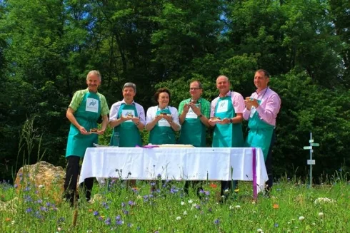 Bild von sechs Personen hinter einem Tisch mit grünen Schürzen gekleidet beim Anschnitt der zweiten Donauwelle