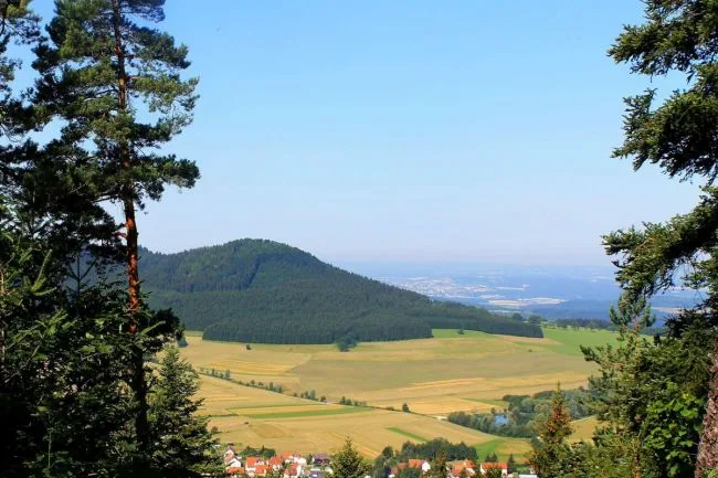 Bild mit Aussicht vom Wandbühl mit Feldern und bewaldetem Berg.