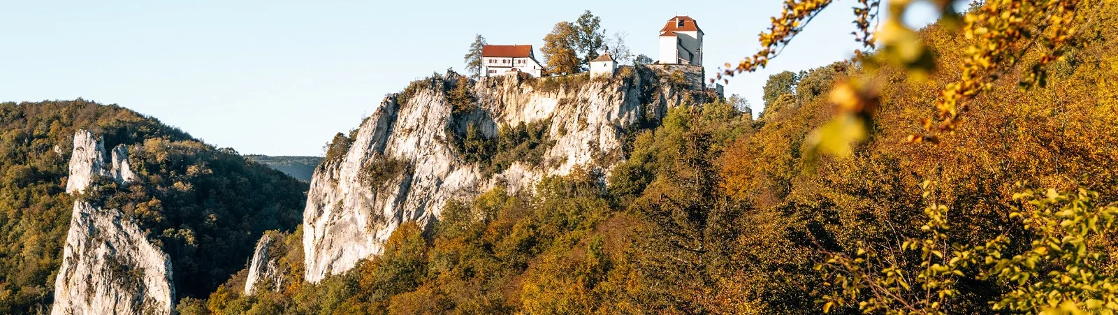 Bild von unten auf das Schloss Bronnen mit herbstlich verfärbten Bäumen im Vordergrund