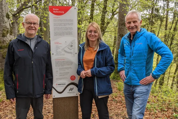 Bild von drei Personen an der Werma-Stele der Ruine Wallenburg im Wald