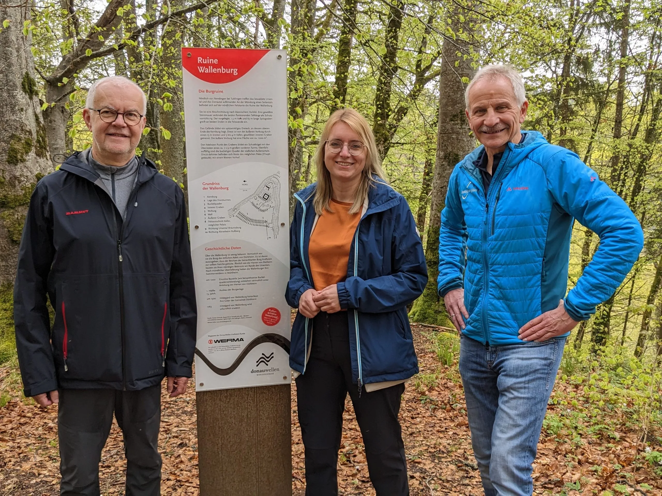 Bild von drei Personen an der Werma-Stele der Ruine Wallenburg im Wald