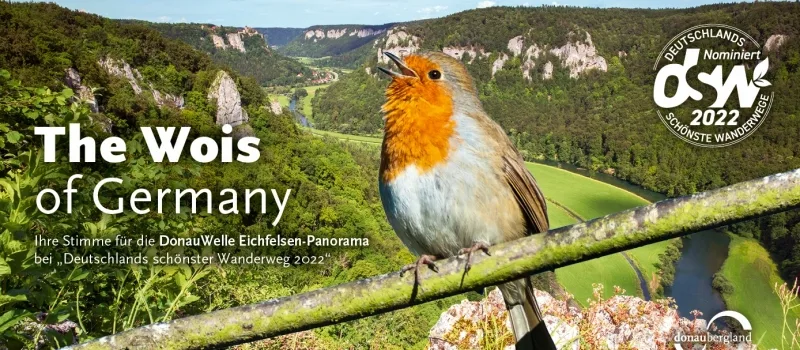 Abstimmungskarte für den schönsten Wanderweg 2022, für den Donauwelle Eichfelsen-Panorama Weg mit Schriftzug The Wois of Germany und einem Rotkelchen im Vordergrund, das auf einem Ast über einem Tal sitzt.