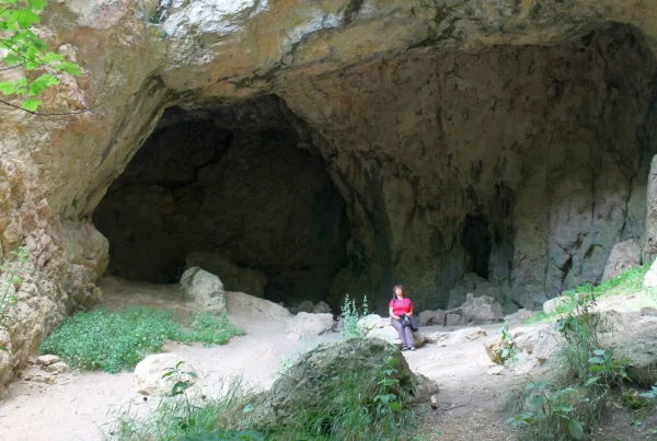 Frau vor einer Höhle sitzend.