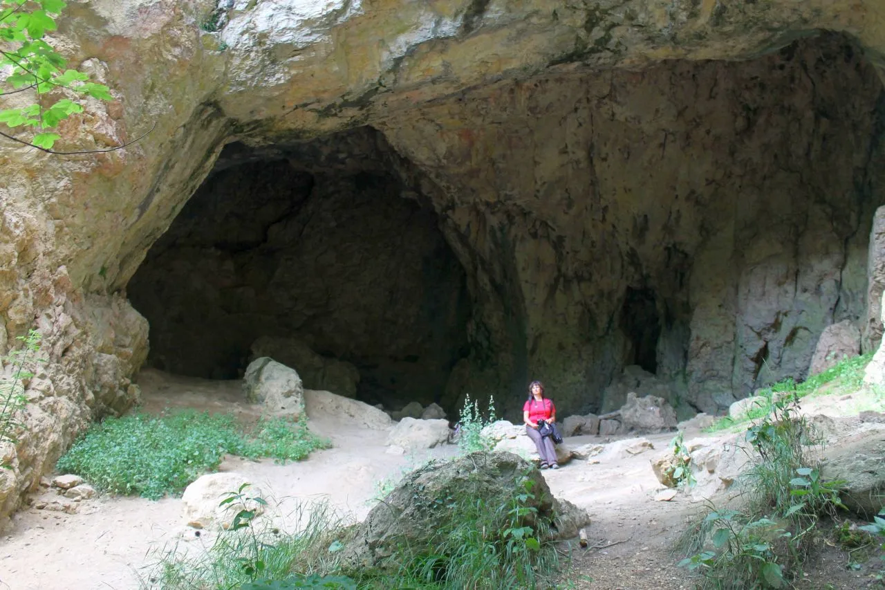 Frau vor einer Höhle sitzend.