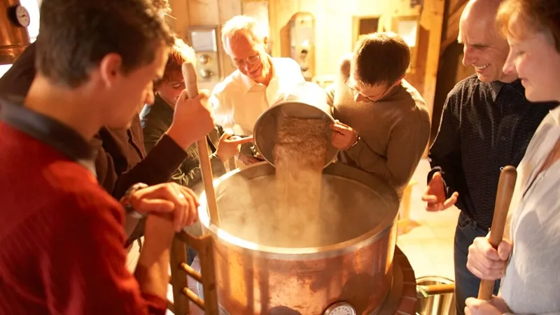 Bild von Personen, die um einen Braukessel in der Hirsch Erlebnisbrauerei stehen