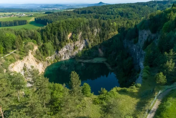 Bild von Blick auf den Kratersee Höwenegg von oben eingebettet in Felsen, Bäumen und Feldern