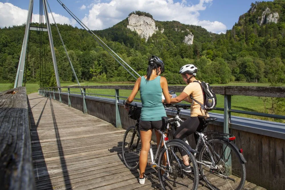 Bild von zwei Radfahrerinnen die auf einer Brücke stehend die Radfahrkarte betrachten.