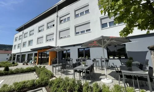 Bild von Front des Schlossberg Hotels mit Gartentischen und Sonnenschirmen