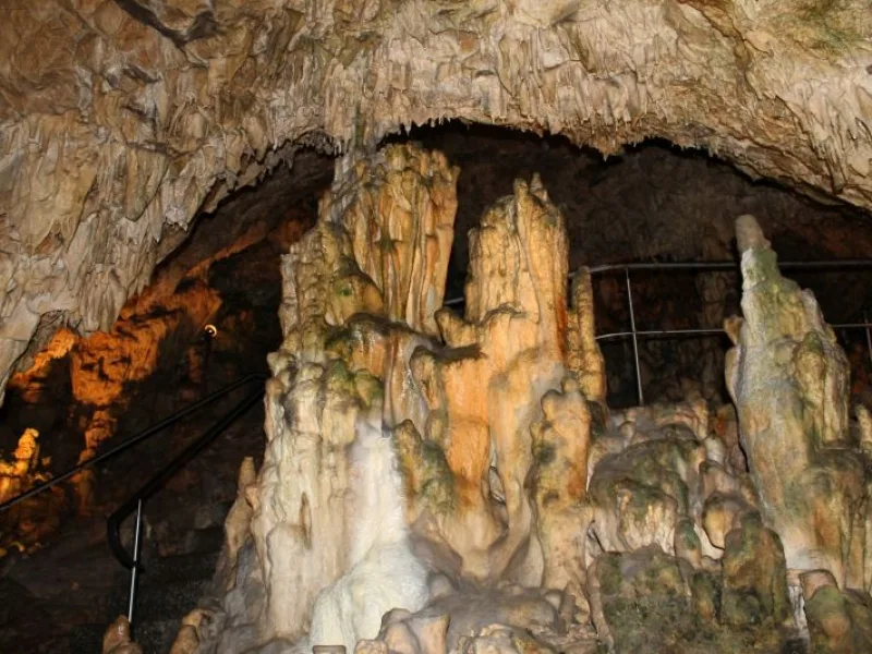 Bild von großen Tropfsteinen in einer Höhle im Hintergrund ist ein Treppengeländer zu sehen