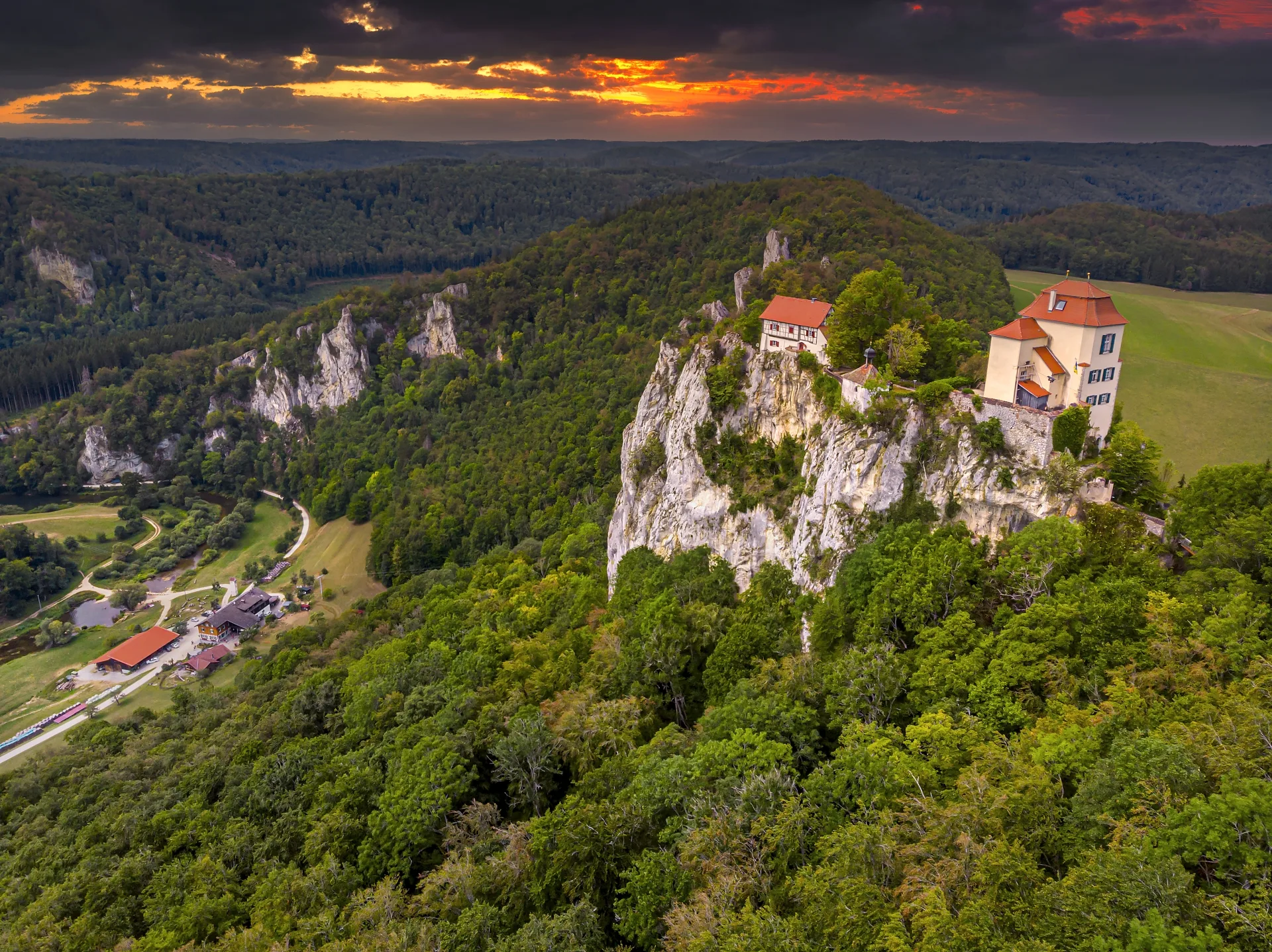 Bild von Schloss Bronnen von oben bei Abendstimmung mit schwarz rot verfärbtem Himmel