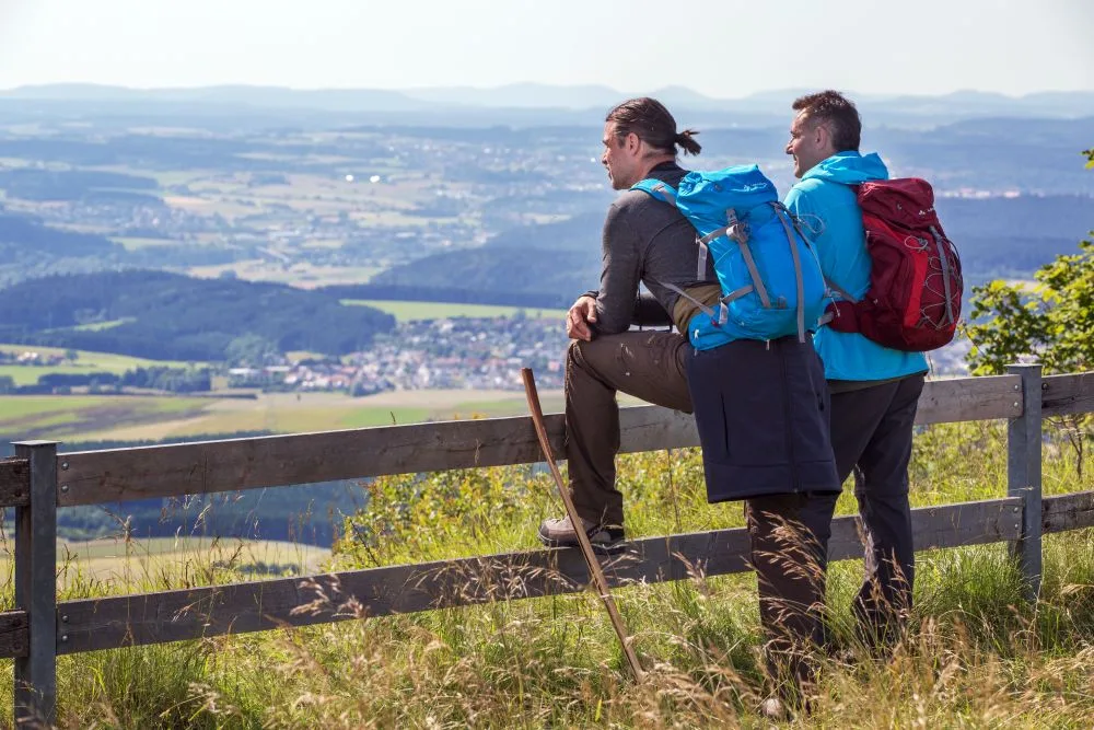 Bild von zwei Wanderern, die am Klippenecksteig in die Landschaft blicken