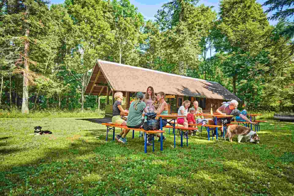 Menschen auf Bänken und an Tischen vor der Wanderhütte