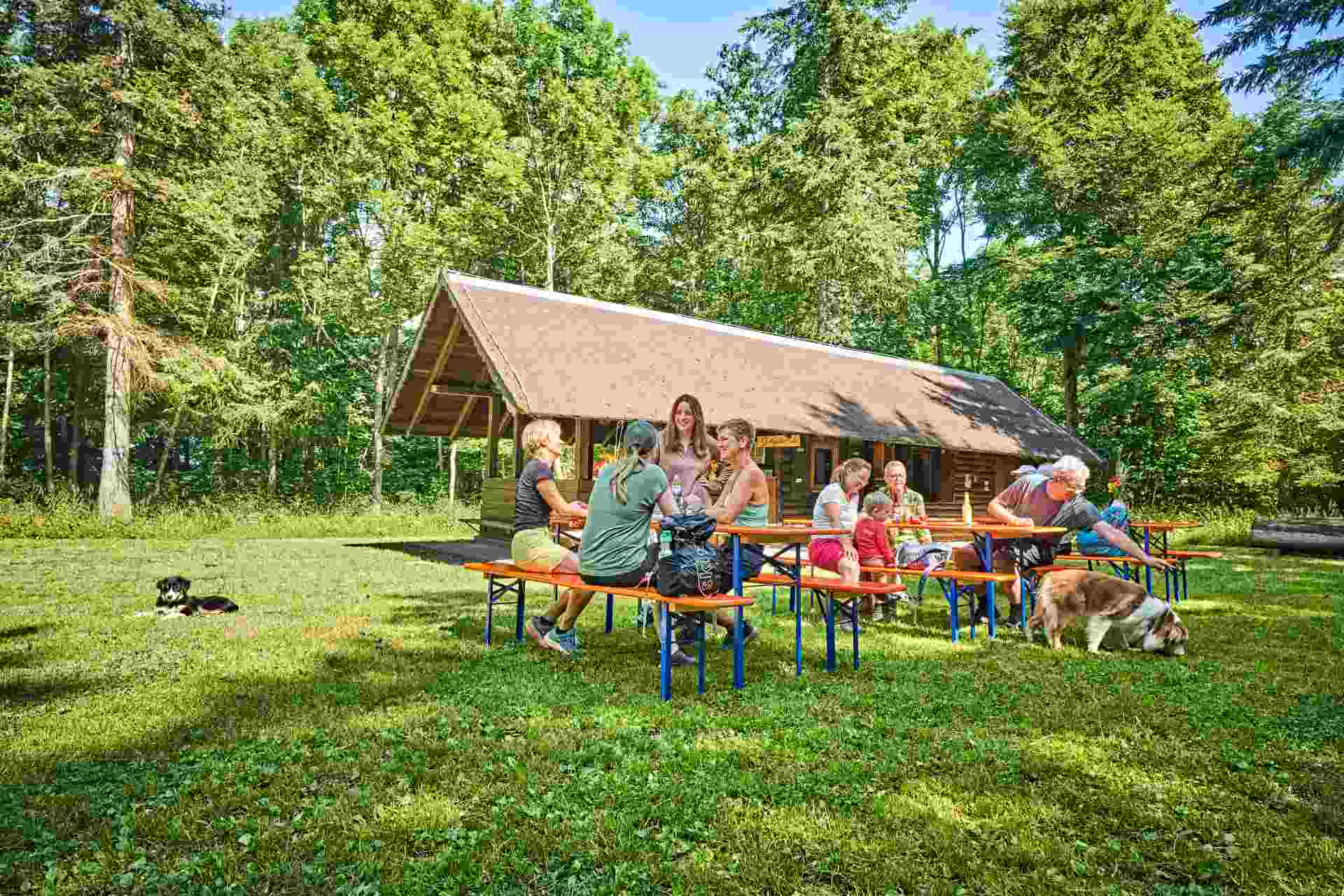 Menschen auf Bänken und an Tischen vor der Wanderhütte
