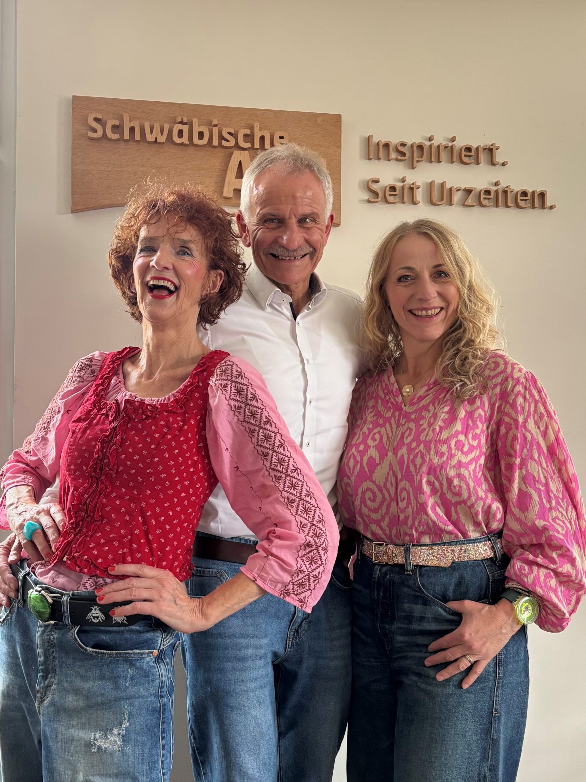 Zwei Frauen, ein Mann in der Mitte vor dem Schwäbische Alb- Schild mit dem Claim Inspiriert. Seit Urzeiten.