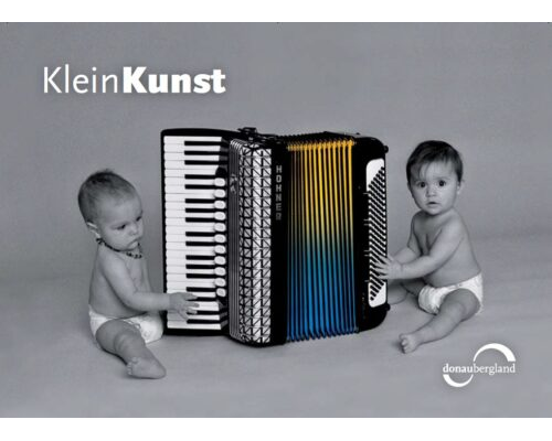 Donaubergland Postkartenmotiv mit zwei Babys, die ein Hohne Akkordeon abtasten.